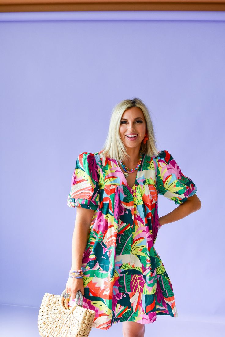 Get ready to turn heads in the Mitzi Print Mini Dress! This playful dress features a tropical floral print in bright, vibrant colors that will make you stand out in any crowd. With beaded buttons and a puff sleeve, this cotton poplin dress is perfect for a day out on the town. Product Details: Measurements: BUST small 19" medium 20" large 21" LENGTH small 35" medium 36" large 37" cotton poplin beaded buttons puff sleeve flowy fit model wearing size small model stats: size 4, 5'5 Vibrant Mini Dress For Day Out, Vibrant V-neck Dress With Tropical Print, Tropical Dress With Vibrant Print For Day Out, Vibrant Tropical Print Short Sleeve Dress, Vibrant Print Short Sleeve Mini Dress For Vacation, Tropical Multicolor Dress With Palm Tree Print, Tropical Multicolor Palm Tree Print Dresses, Tropical Multicolor Mini Dress For Vacation, Vibrant Floral Print Mini Dress