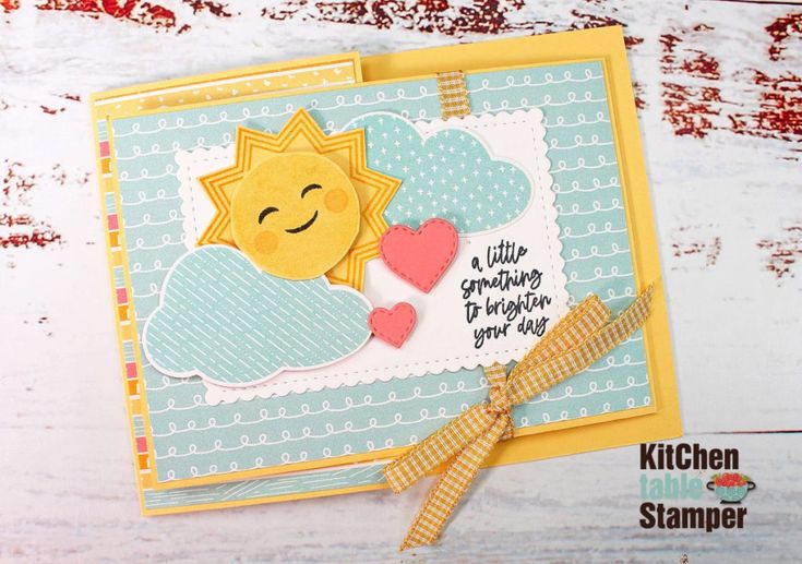 a close up of a card with a sun and clouds on it, sitting on a table