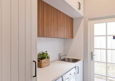 a laundry room with white walls and wooden cabinetry next to a sliding glass door