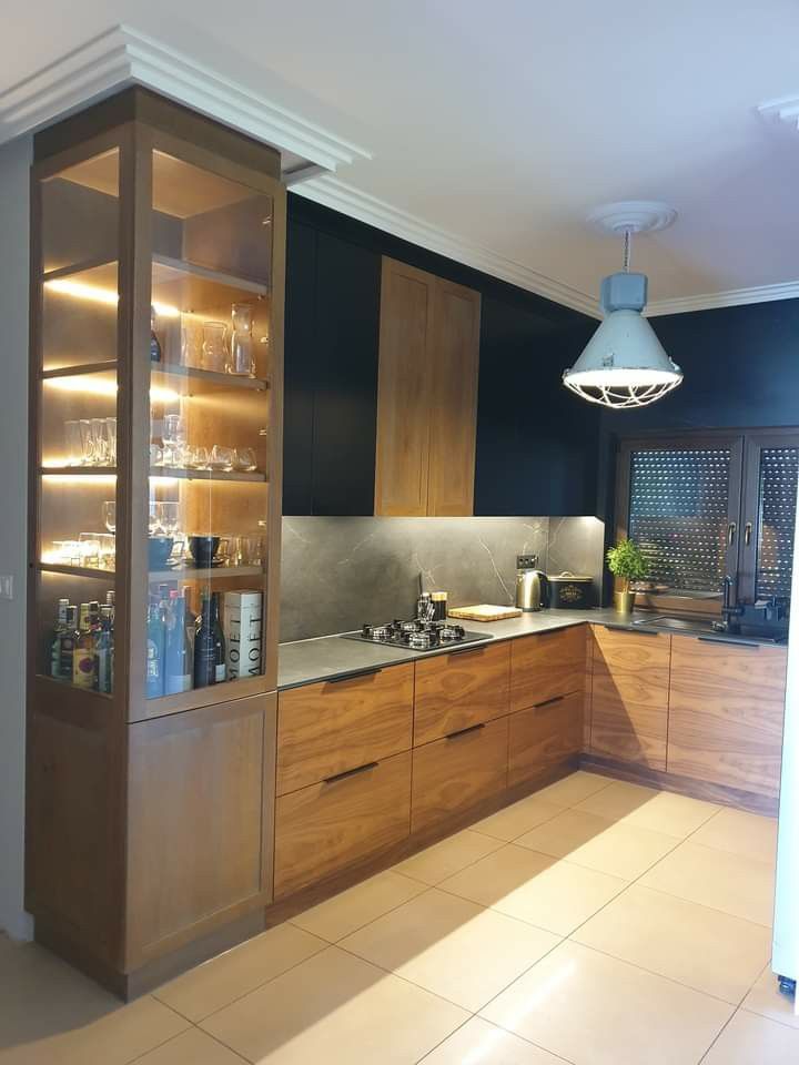 a modern kitchen with wooden cabinets and glass front cupboards on the wall, along with white tile flooring