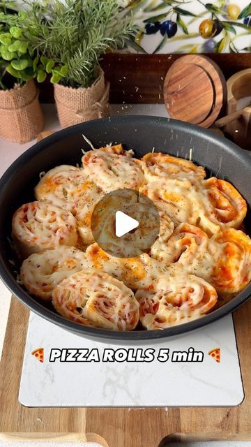 a pan filled with pizza rolls sitting on top of a wooden table next to potted plants