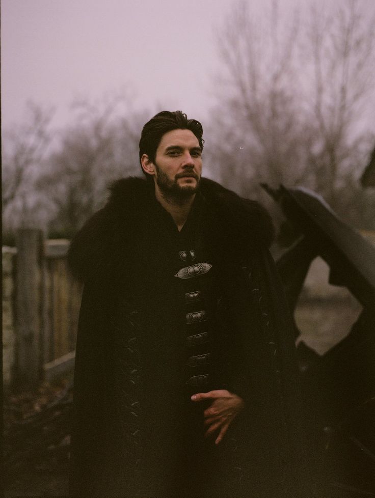 a man wearing a black coat standing next to a car