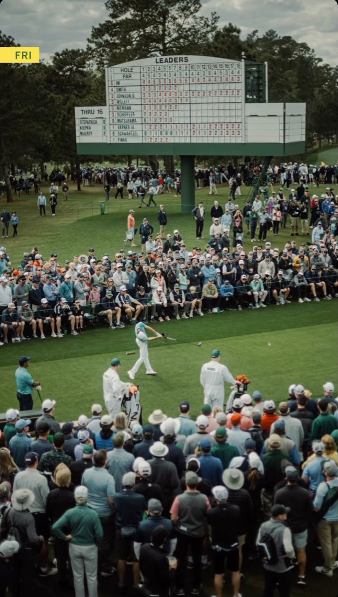 a large group of people standing on top of a field next to a scoreboard