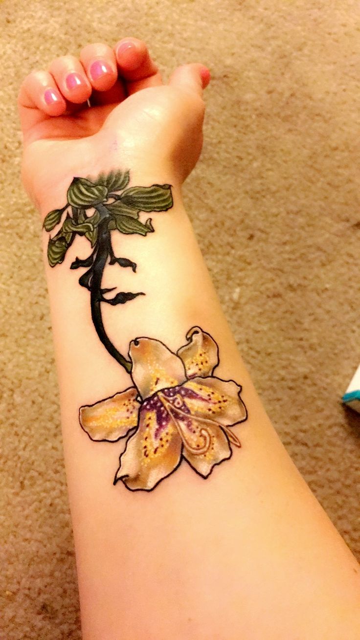 a woman's arm with a flower tattoo on her left wrist and the bottom half of her arm