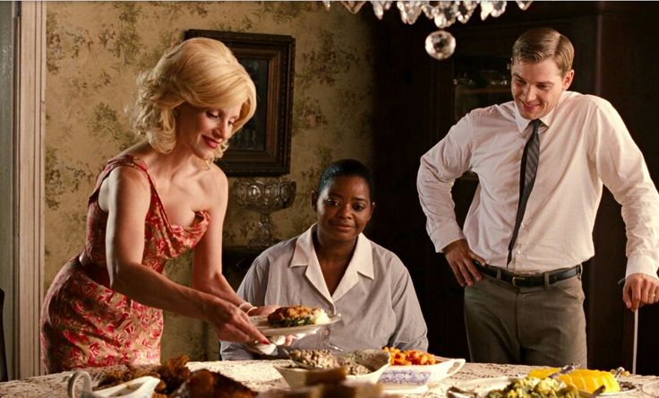 a man and woman standing in front of a table with plates of food on it