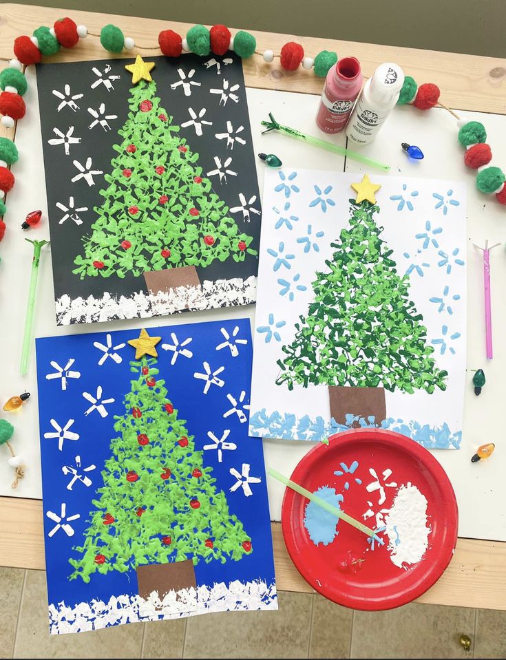 three paper plates with christmas trees on them next to crafting supplies and paintbrushes