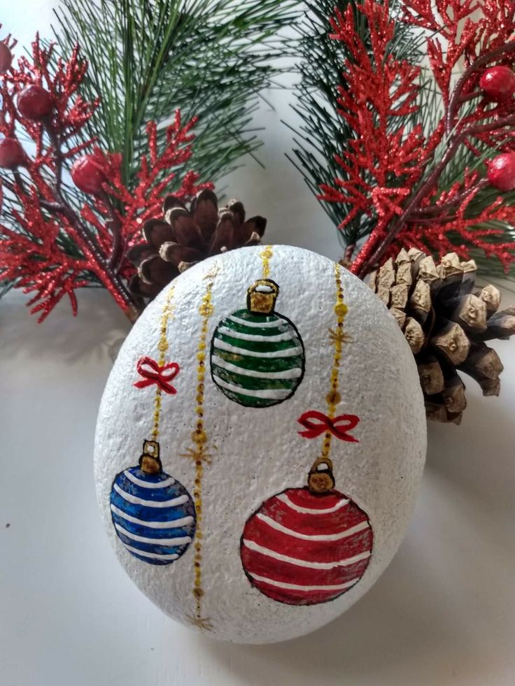 a rock with ornaments painted on it next to pine cones