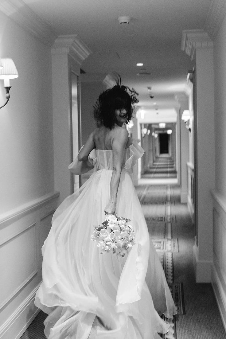 a woman in a wedding dress walking down a hallway