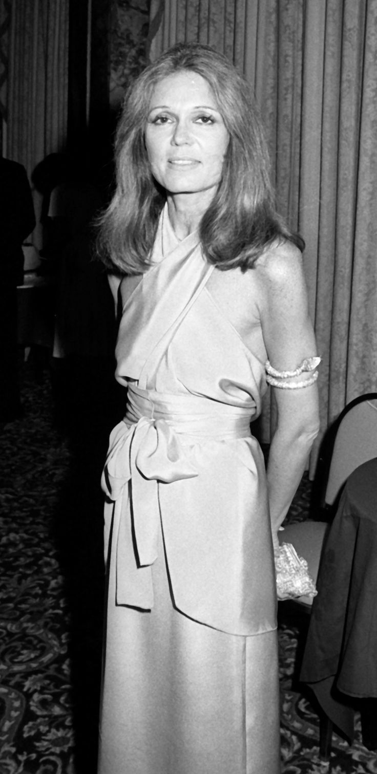 an old black and white photo of a woman in a dress posing for the camera