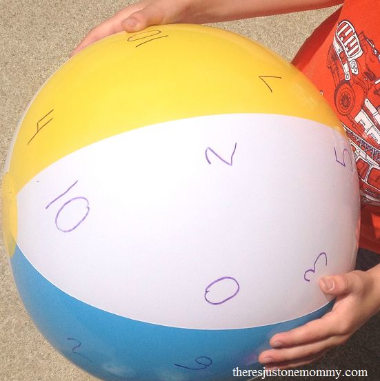 a child holding a large beach ball with numbers on the top and bottom, in front of him