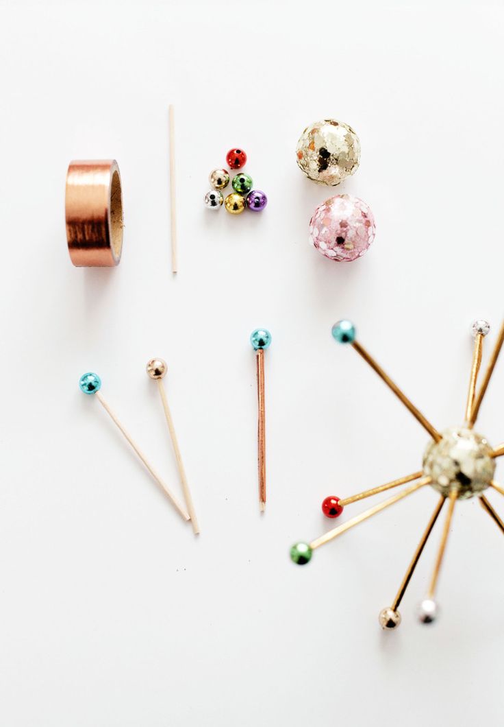 an assortment of pins, needles and beads on a white surface