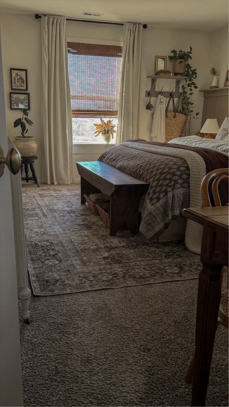 a bed room with a neatly made bed next to a window and a rug on the floor