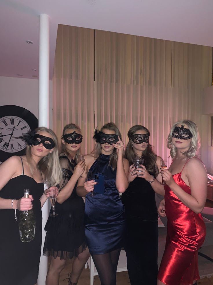 a group of women standing next to each other wearing blindfolds and holding wine glasses