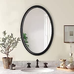 a bathroom sink with a round mirror above it and plants on the counter next to it