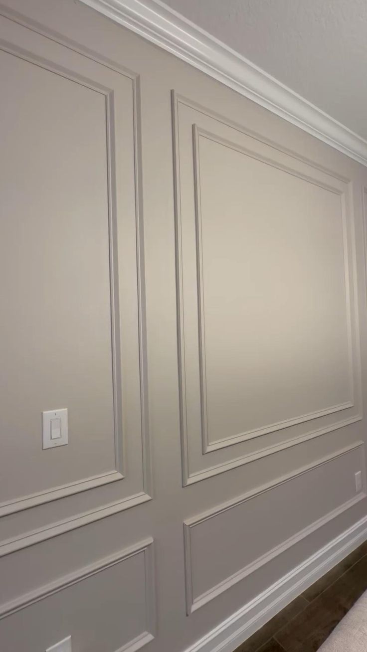 an empty room with white paneled walls and wood flooring on the side wall