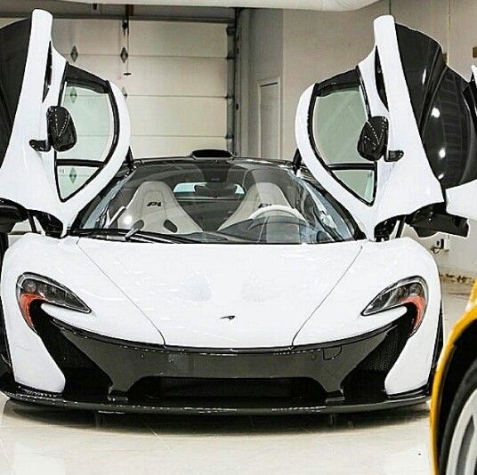 a white and black sports car in a garage with its doors open to reveal the interior