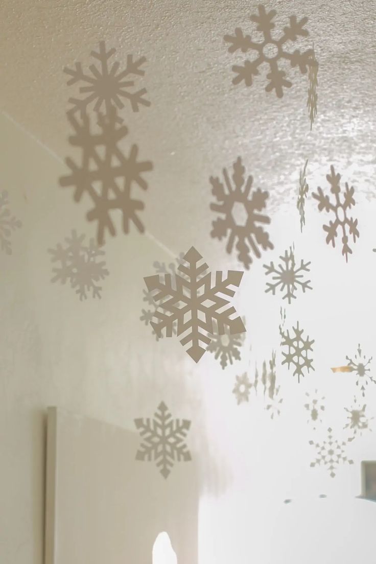 snowflakes are hanging from the ceiling in front of a mirror with light shining on them