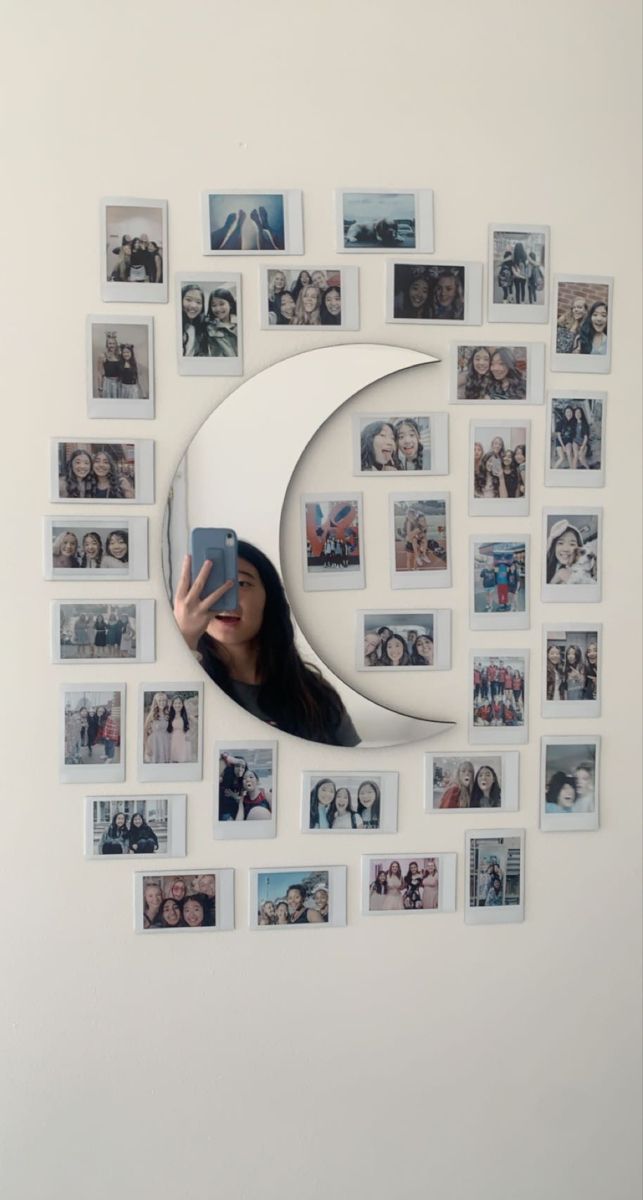 a woman taking a selfie in front of a wall with many pictures on it