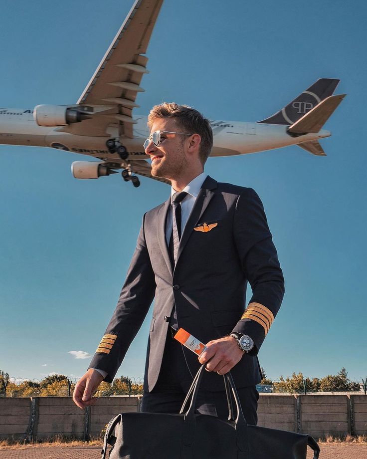 a man in a suit and tie carrying a duffel bag next to an airplane