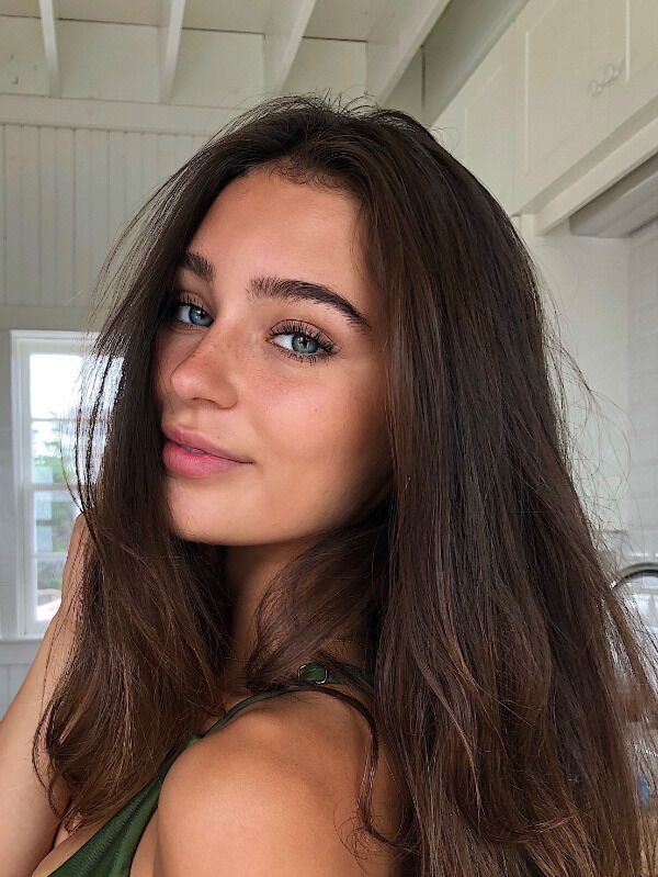 a woman with long brown hair is posing for the camera and looking at the camera