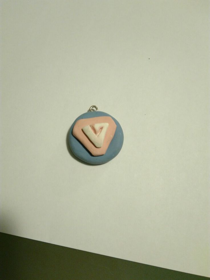 a blue and pink pendant with a white triangle on it's center, sitting on top of a table