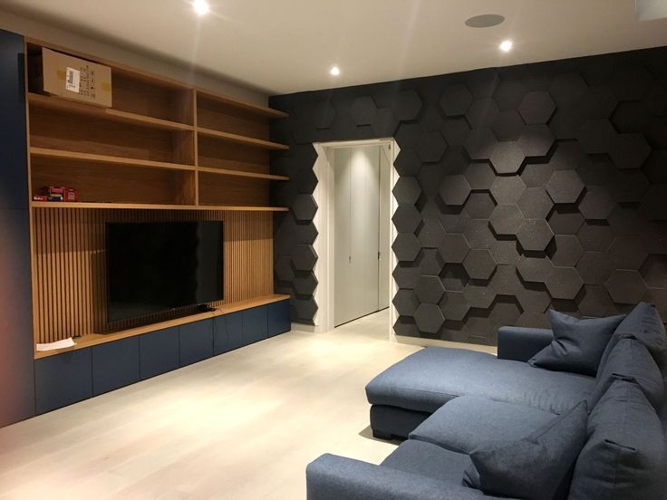 a living room filled with furniture and a flat screen tv mounted on a wall next to a wooden shelf