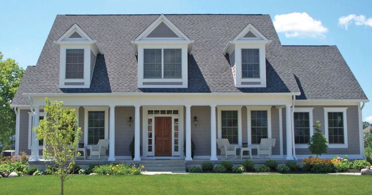 a large gray house with white trim on the front and side windows is shown in this image