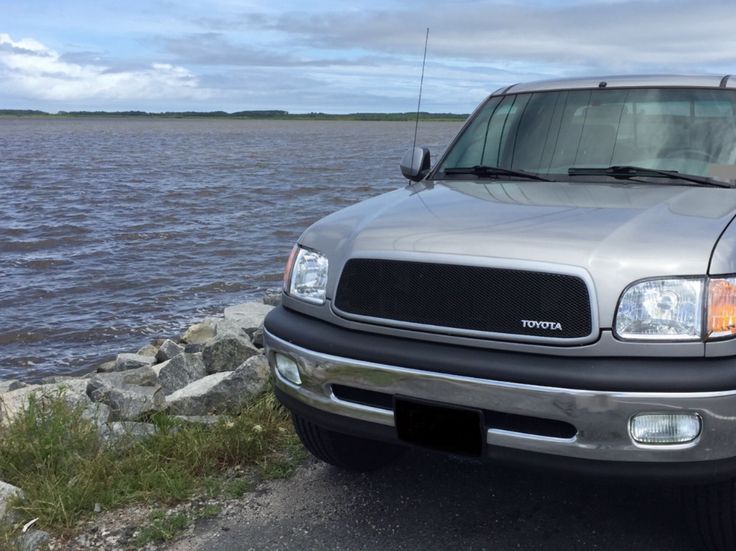 a silver truck parked on the side of a road next to a body of water