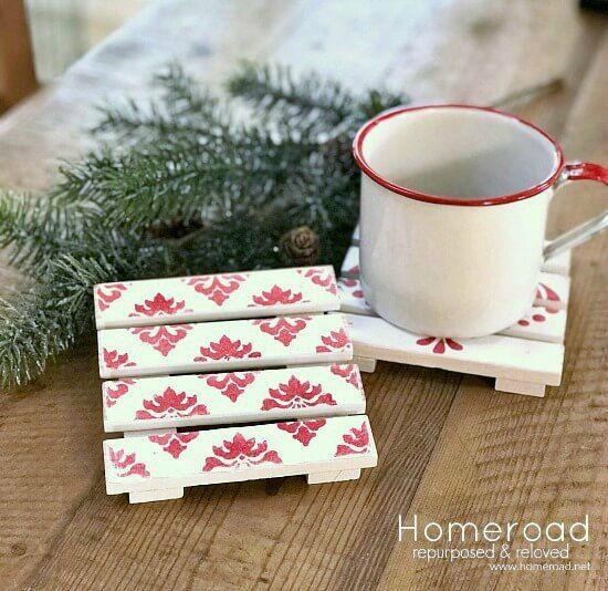 small coasters with red and white designs sit on a table next to a cup