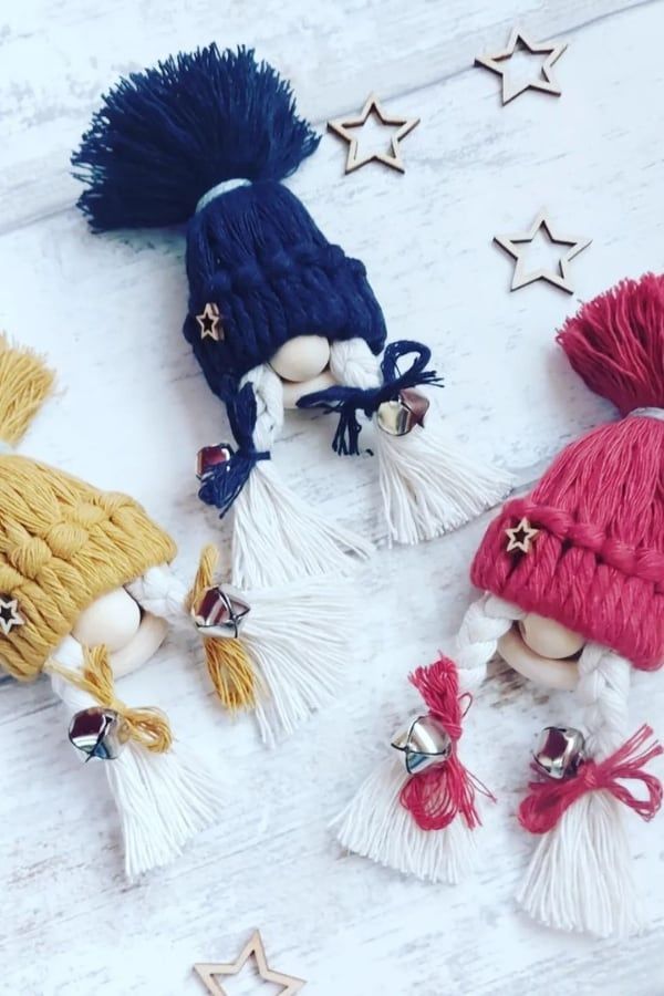 three small dolls wearing hats and tassels on top of a white wooden table