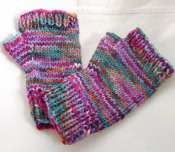 a pair of colorful knitted mittens sitting on top of a white tablecloth