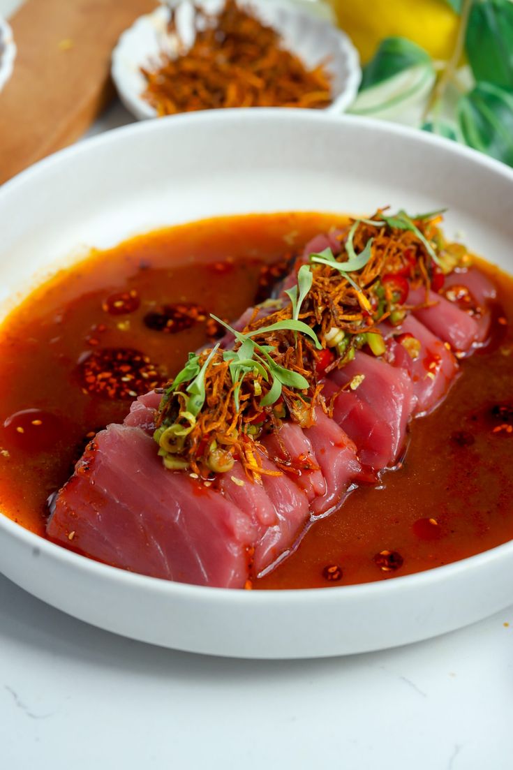 a white bowl filled with meat covered in sauce