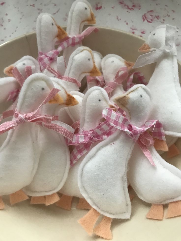 small stuffed birds in a bowl with pink ribbon on the sides and bows tied around them