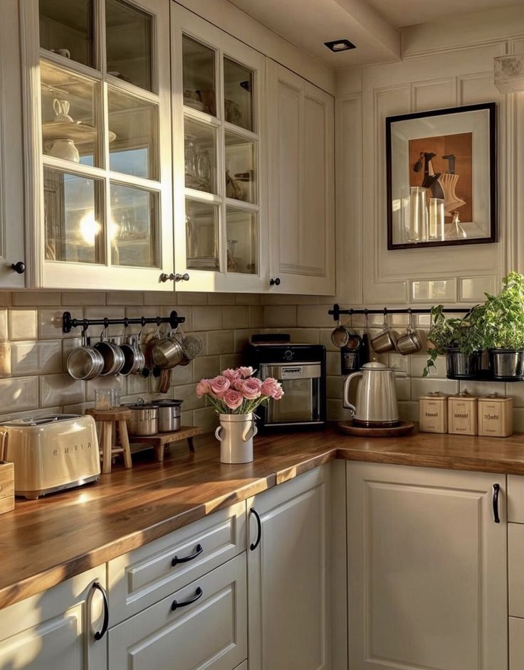 a kitchen with white cabinets and wooden counter tops is pictured in this image, there are flowers on the counter