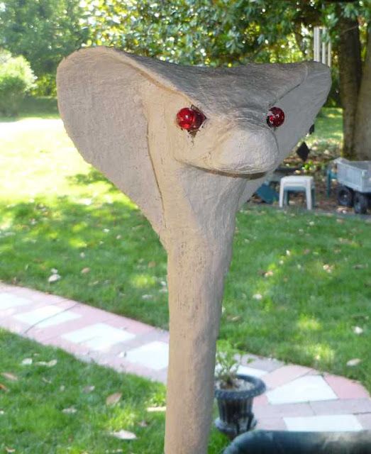 an elephant statue with two red eyes on it's head, in the grass