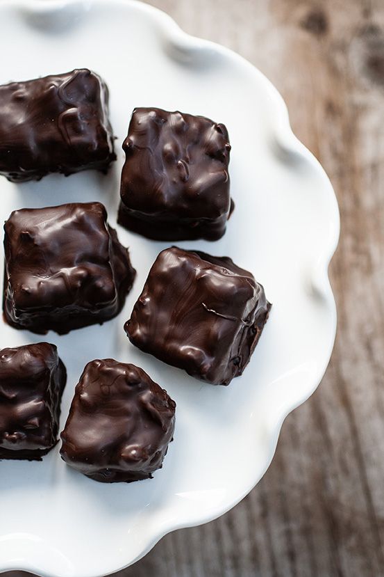 several pieces of chocolate on a white plate with a wooden table in the back ground