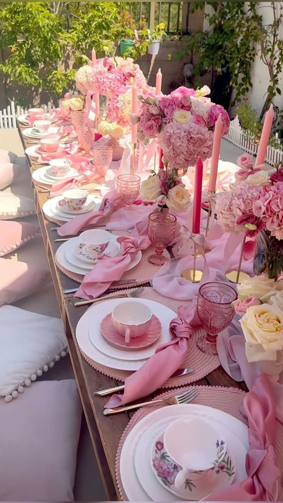 the table is set with pink and white plates, napkins, and vases