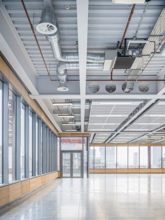 an empty room with large windows and lots of light coming from the overhead lighting fixtures