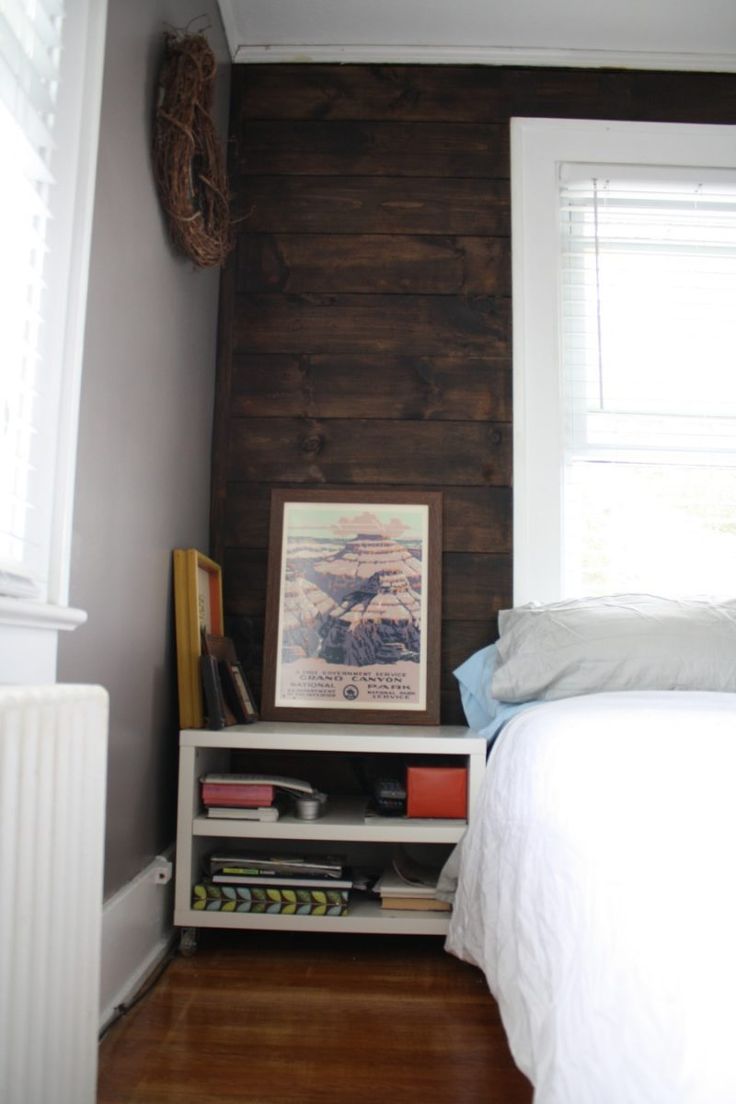 a bedroom with wood paneling on the wall and a bed in front of it