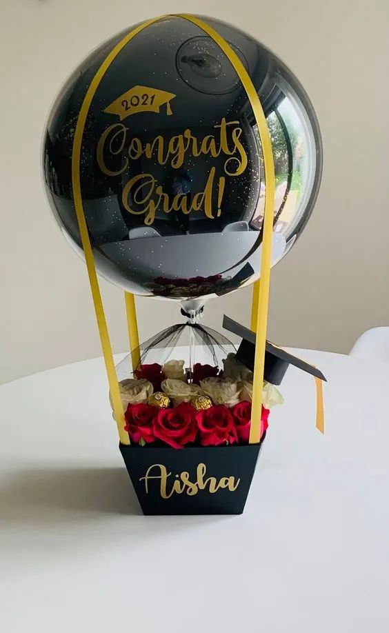 a graduation balloon with flowers in it sitting on a table