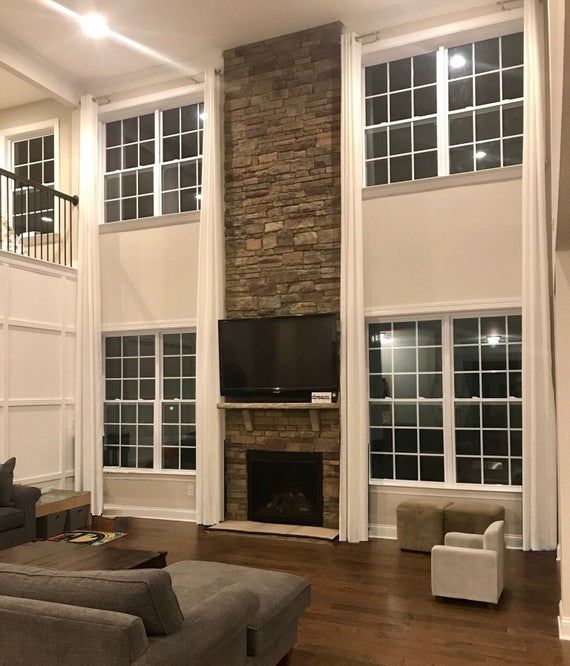 a living room with two couches and a tv on the wall in front of a stone fireplace