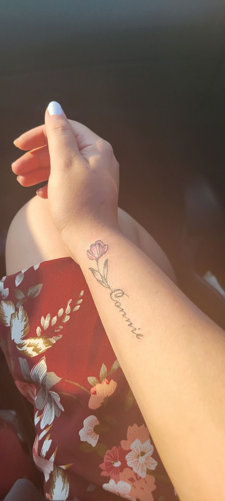 a woman's arm with a flower tattoo on the left side of her arm