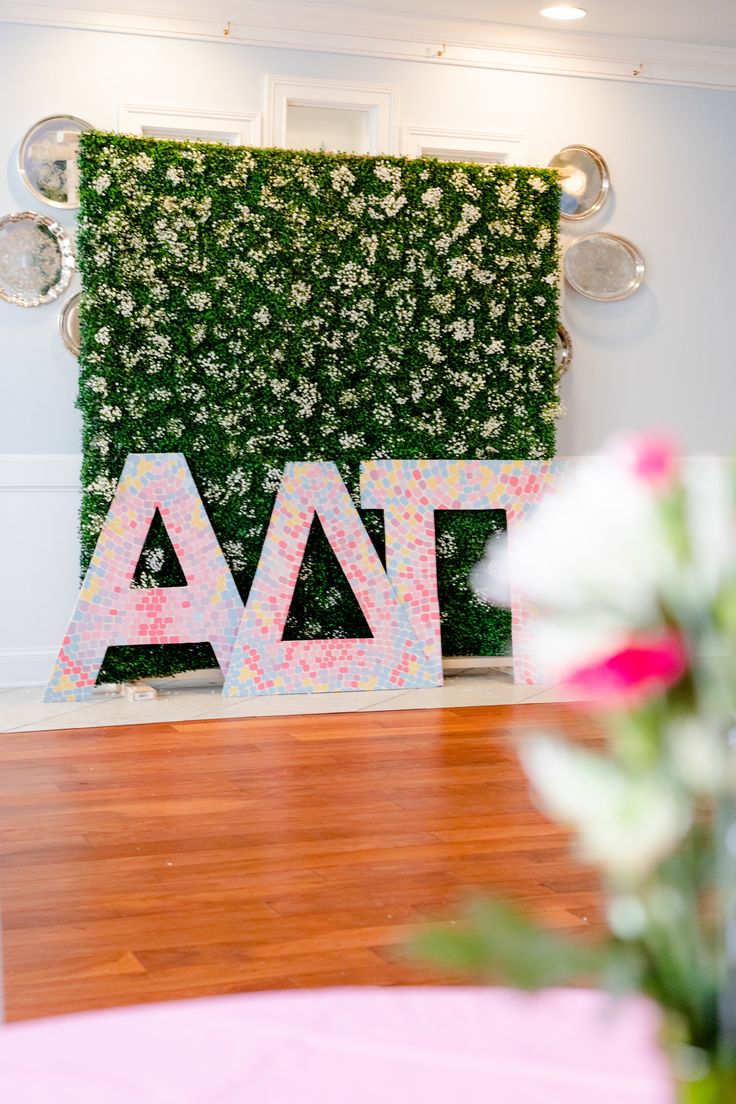 a green wall with letters and flowers on it