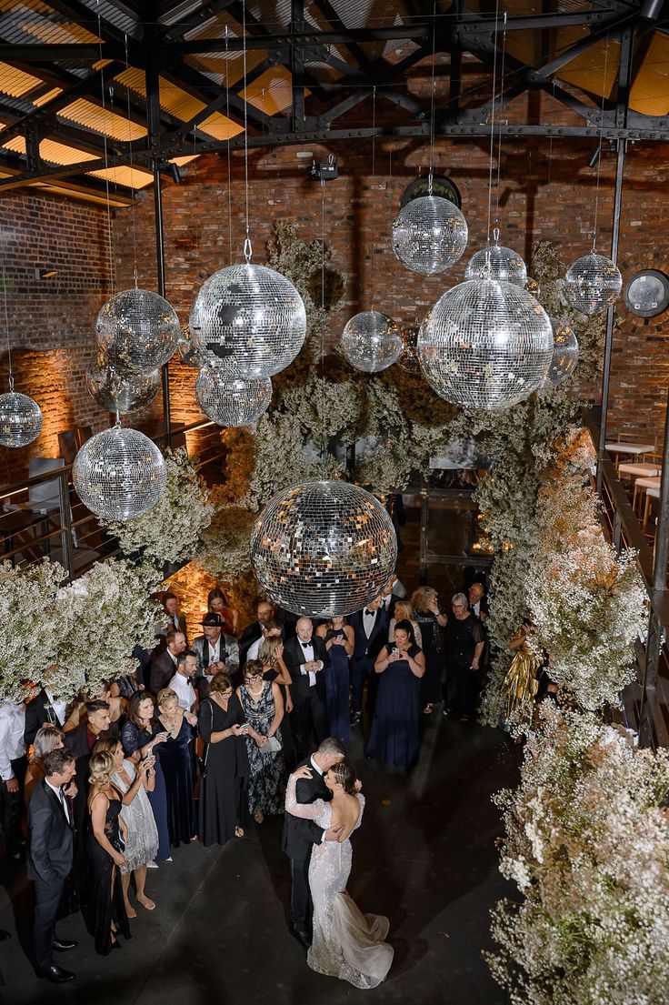 a group of people standing around each other in front of disco ball chandeliers