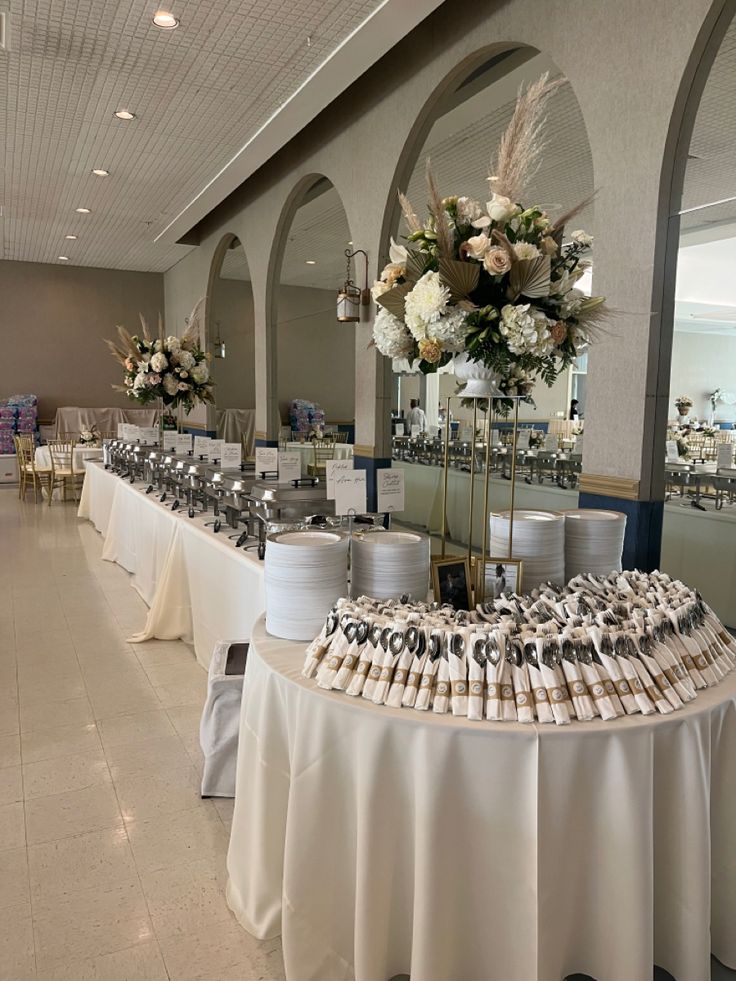 a banquet hall with tables and chairs covered in white linens, decorated with flowers