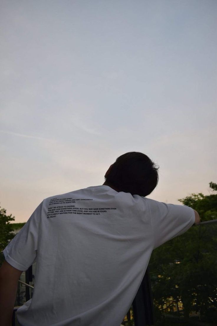 a man is looking at the sky with his back turned to the camera while standing on a balcony