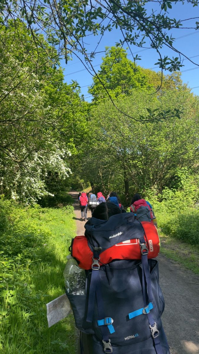 a group of people walking down a path with backpacks on their backs and back