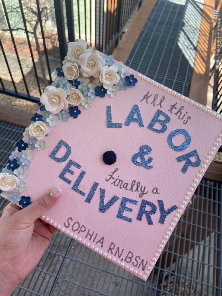 a hand holding up a pink sign with flowers on it that says labor and delivery