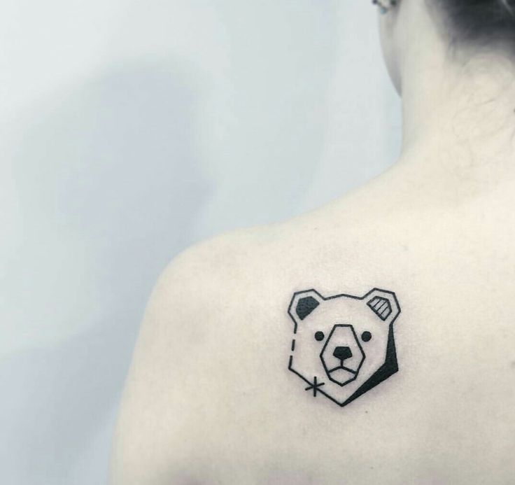 a woman with a bear tattoo on her upper back shoulder and chest, looking at the camera