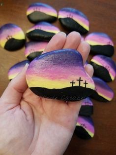 a hand holding a painted rock with crosses on it